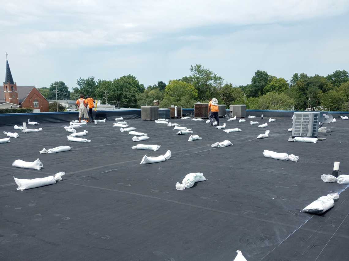 The installation of sand bags to ballast (hold down) a wind damaged roof. All Seasons Roofing - storm damage